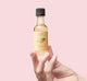 Hand holding FarmHouse Fresh Clementine body oil Deluxe Sample with citrus scent.
