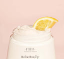 A jar of Mellow Moon Dip Relaxation Body Mousse by FarmHouse Fresh with a slice of lemon in it that represents the delicious lemon cream scent of the product.