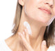 A woman is applying FarmHouse Fresh Necks-Level Smooth Neck Cream to make her neck smoother and younger looking.