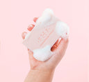 A hand holding a bar of softly scented FarmHouse Fresh Pink Moon Shea Butter Bar Soap with rich lather on it.