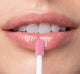 A woman is applying FarmHouse Fresh Vitamin Glaze Lip Gloss in Delicate Rose color that hydrates  to lips.