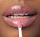 A woman is applying FarmHouse Fresh Vitamin Glaze Lip Gloss in Delicate Rose color that restores dull lips.