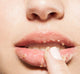 A close up of a woman's mouth with a finger on it, featuring Farmhouse Fresh's Beach Punch® lip polish from Beach Lip Gift Basket with natural and exfoliating lip products.