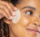 A woman is swiping her face with FarmHouse Fresh C of Change Clinical Peel Pad to brighten her face and clear acne.