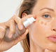 A woman is applying FarmHouse Fresh Chocolate Fig Vitamin Recovery Serum onto her face to deeply hydrate her skin.