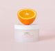 A jar of FarmHouse Fresh C of Change Clinical Peel Pads with half an orange on top of it, representing the natural ingredients of this skincare product.