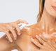 A woman is applying FarmHouse Fresh Lustre Drench Instant Glow Dry Oil on her body for all-natural fake tan.