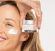A woman holding a jar of FarmHouse Fresh Moon Dip Facial Mousse with anti-aging and wrinkle-fighting properties.
