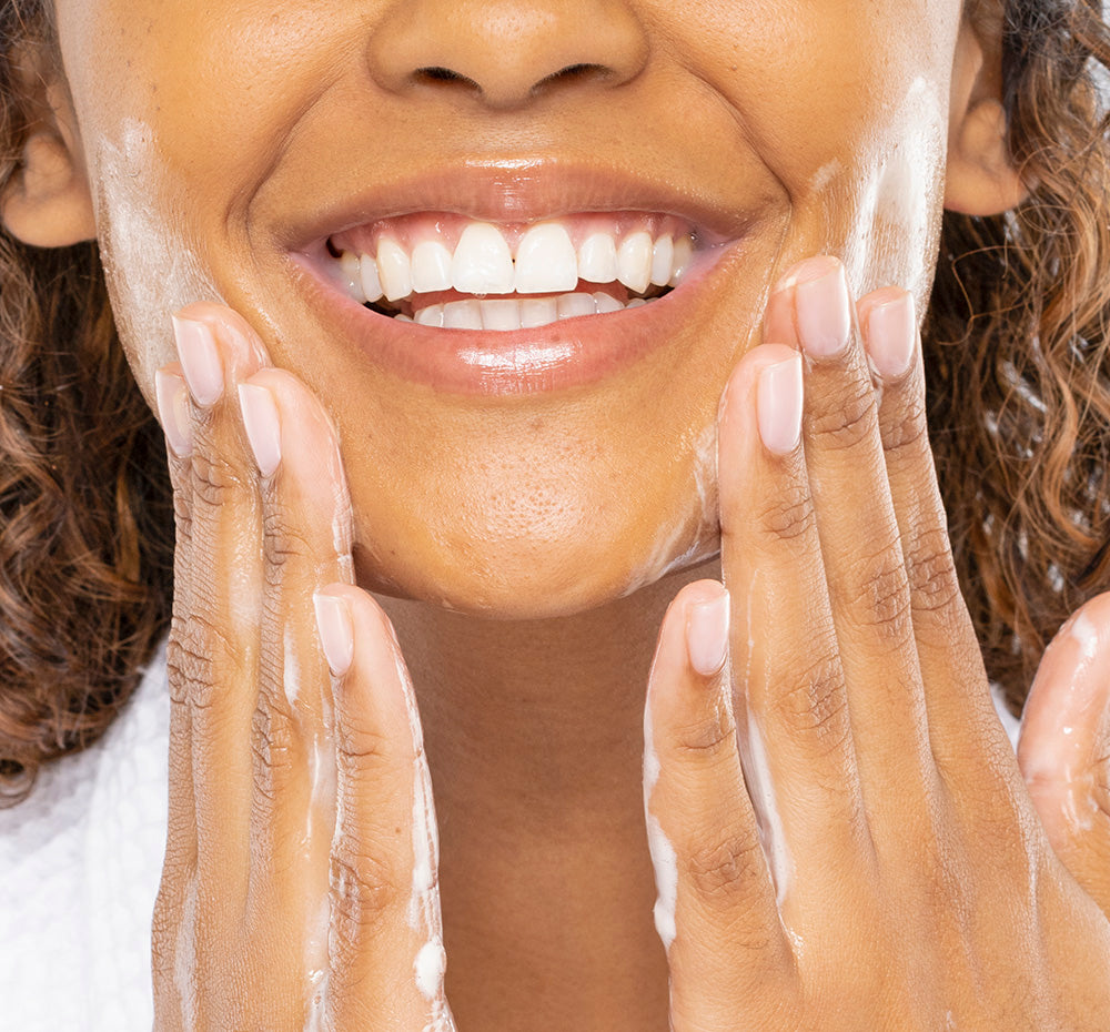 A woman is washing her face with FarmHouse Fresh New Groove Gel Cleanser made with calming cannabinoid-rich full spectrum hemp oil.