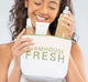 A woman holding signature FHF Canvas Cosmetic Bag with Farmhouse Fresh logo on it with skincare products peeking out of the bag.