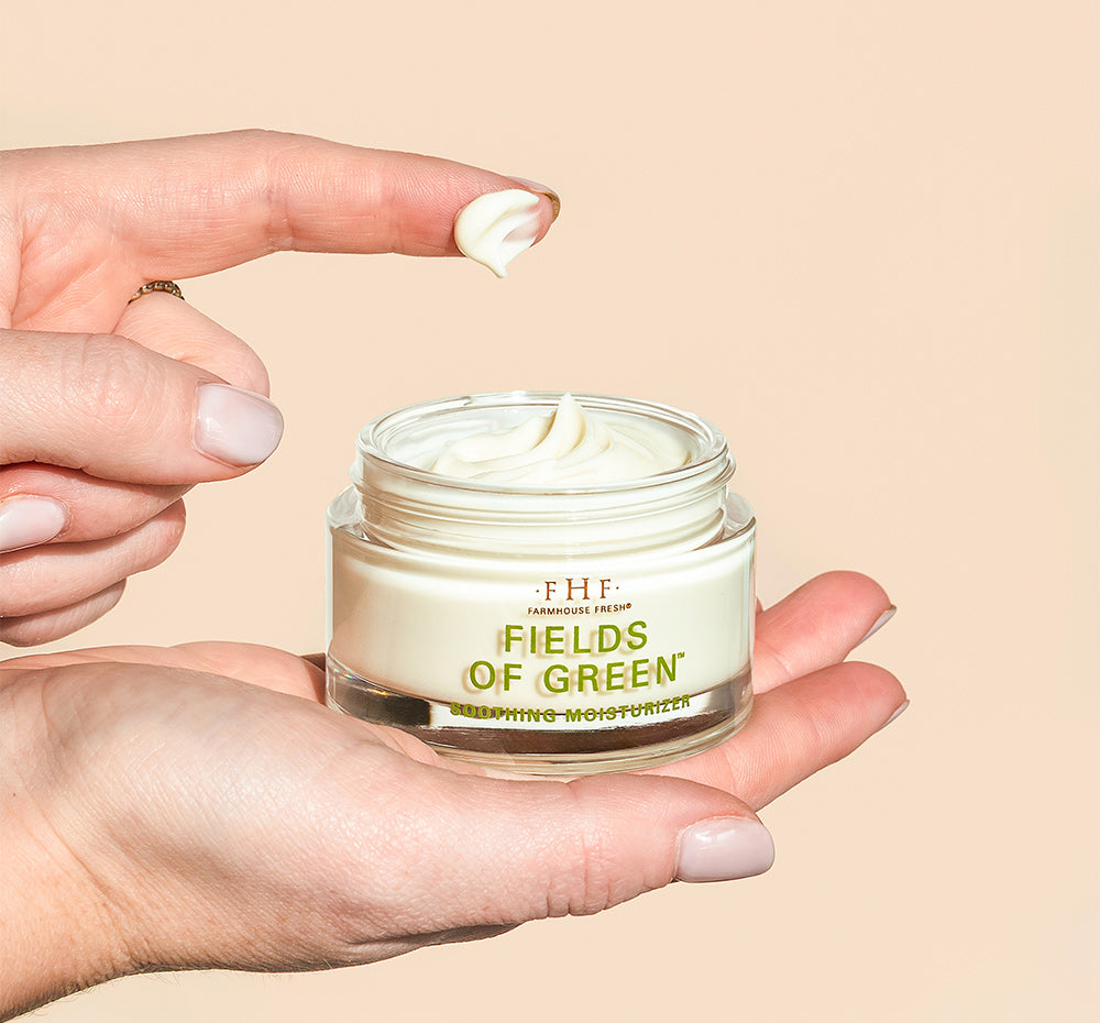 Person’s hands holding an opened jar of FarmHouse Fresh Fields of Green Organic Matcha Ultra-Soothing Face Moisturizer that calms rosacea flares.