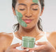 A woman holding up Farmhouse Fresh Guac Star Soothing Avocado face mask, which is hydrating and cooling.