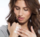 A woman is applying FarmHouse Fresh Island Elixir Organic Hand Cream on her hand to soothe and moisturize her dry skin.