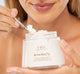 A woman is holding a jar of Mellow Moon Dip Body Mousse with CBD by FarmHouse Fresh, showing its light and whipped texture.