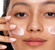 A woman is applying FarmHouse Fresh Midnight Clearing Night Lotion on her face to clear and soothe her complexion.