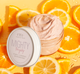 A jar of FarmHouse Fresh Mighty Brighty Vitamin C + Chamomile Brightening Mask on top of orange slices that represent the natural ingredients and the citrusy scent of the product.