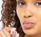 A woman is showing her hydrated and natural looking pink lips after using FarmHouse Fresh Strawberry Mood Fruit Lip balm.