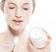 A woman is holding a jar of Serene Moon Dip Body mousse and an applicator wand, ready to nourish and soften her skin.