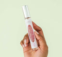 A hand holding all-natural Pink Moon Travel Spray Perfume by FarmHouse Fresh with a soft, delicate scent.