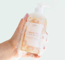 A hand holding FarmHouse Fresh Sunshine Silk Soothing Body Wash made with skin calming botanical extracts like green tea and chamomile.