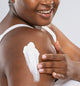 A woman is applying on her arm rich moisturizing Sunshine Silk shea butter by FarmHouse Fresh to calm her dry skin.