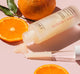 An opened bottle of FarmHouse Fresh Vitamin C with serum pouring out of it, revealing a thick, rich texture, surrounded by oranges that represent the natural and locally sourced ingredients.