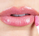 A woman is applying FarmHouse Fresh Vitamin Glaze Oil Infused Lip Gloss in subtle, barely-there Sheer Pink color.
