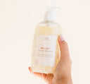 A hand holding FarmHouse Fresh Whoopie Soothing Body Wash made with skin calming botanical extracts like green tea and chamomile.