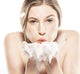 A woman blowing on a rich lather of Whoopie body wash by Farmhouse Fresh, scented like a freshly baked cake.