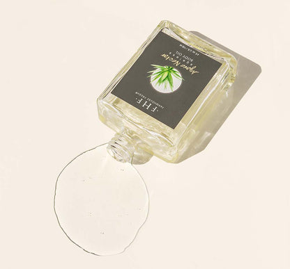 A bottle of FarmHouse Fresh Agave Nectar Ageless Body Oil on its side with oil spilling out of it.