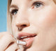 A woman is applying creamy, long-lasting Farmhouse Fresh Blackberry Crush Lip Balm for added softness.