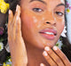 A woman with FarmHouse Fresh Blue Lotus Hydration Cascade Moisturizer on her face, showing her hydrated skin with a beautiful glow.