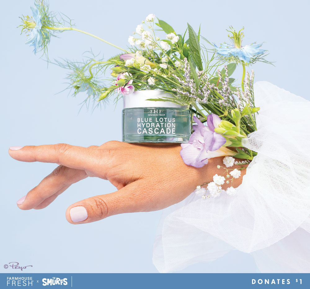 A hand holding a jar of FarmHouse Fresh Smurf collab Blue Lotus Hydration Cascade Face Moisturizer. Each purchase helps save animals.