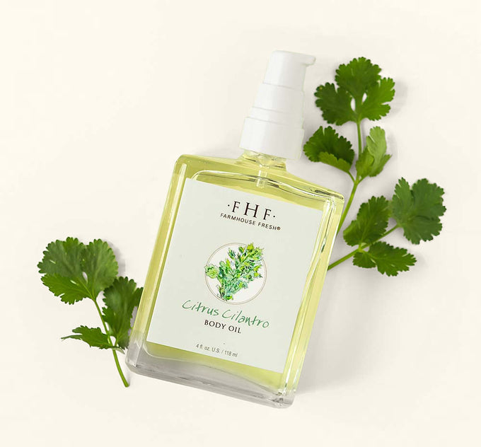 A bottle of refreshing Citrus Cilantro body oil on a green background.