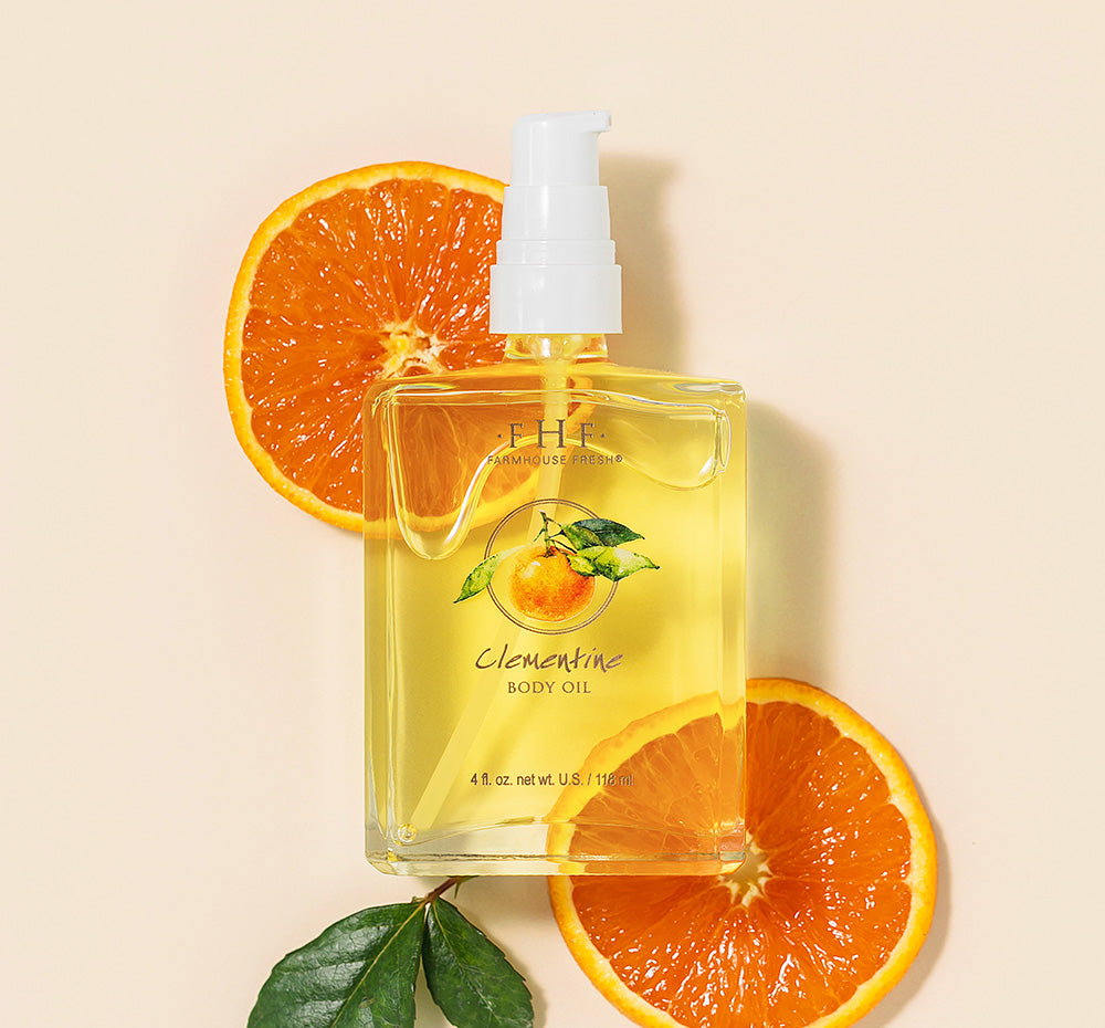 A bottle of light, citrusy Clementine Body Oil by FarmHouse Fresh on top of orange slices.