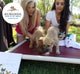 Two women, certified FHF Dog Bed Fairies, are playing with shelter puppies on a Kuranda bed donated from purchases of "Is it True, They Call You the Dog Bed Fairy?" Donation Book by FarmHouse Fresh.
