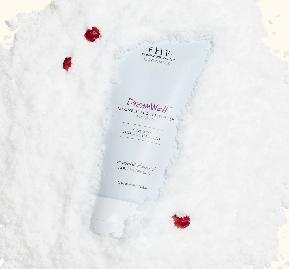 FarmHouse Fresh Dreamwell Magnesium Shea Butter Body Cream surrounded by snow and red rose petals for the holidays
