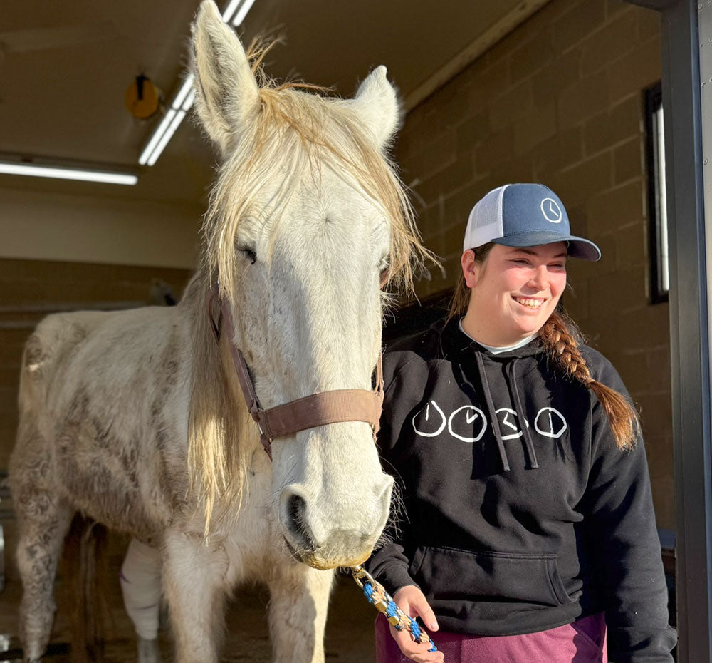 A person standing with a starved white horse