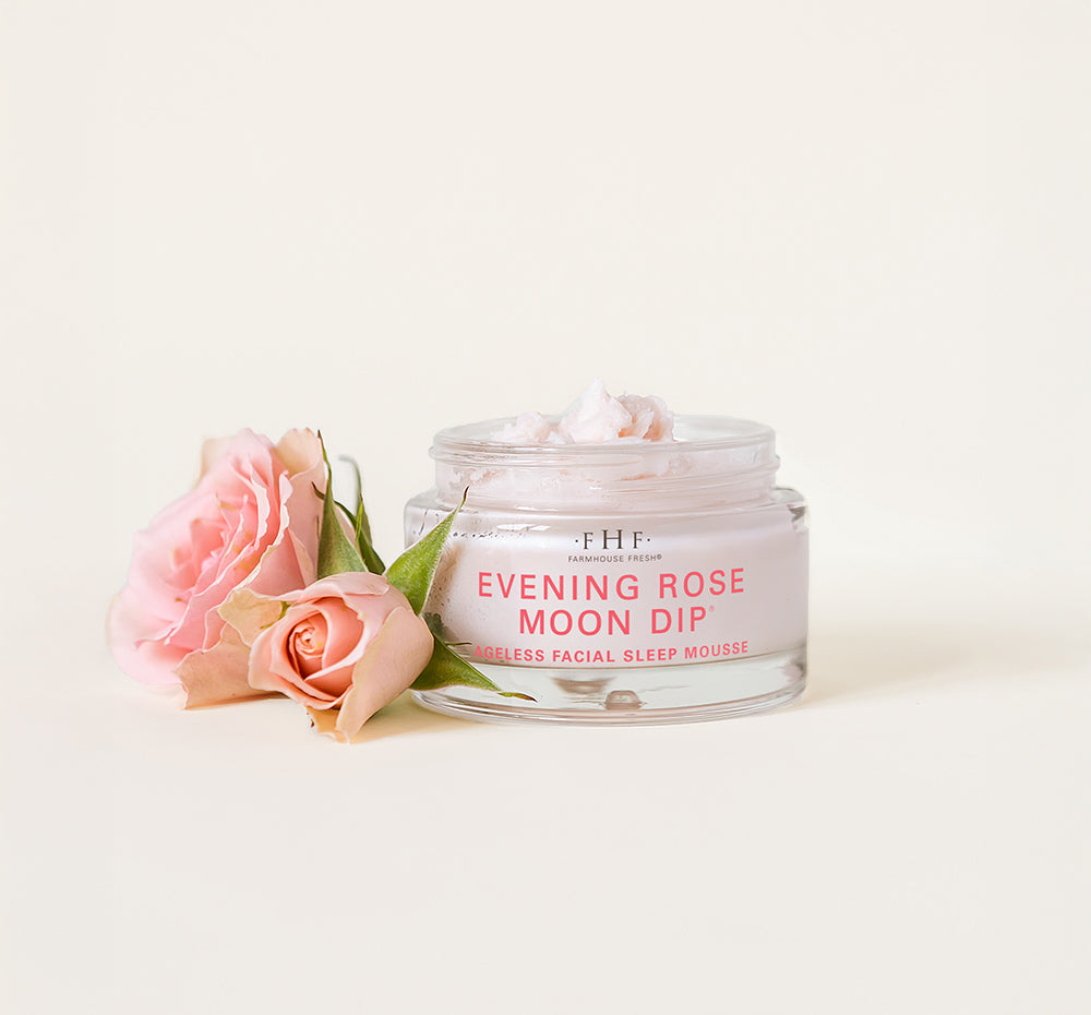A jar of FarmHouse Fresh Evening Rose Moon Dip Ageless next to roses