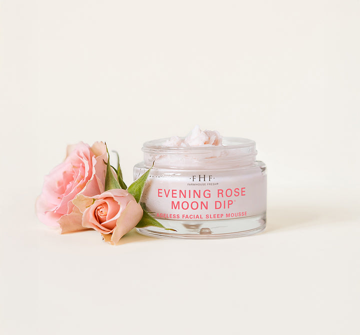 A jar of FarmHouse Fresh Evening Rose Moon Dip Ageless next to roses