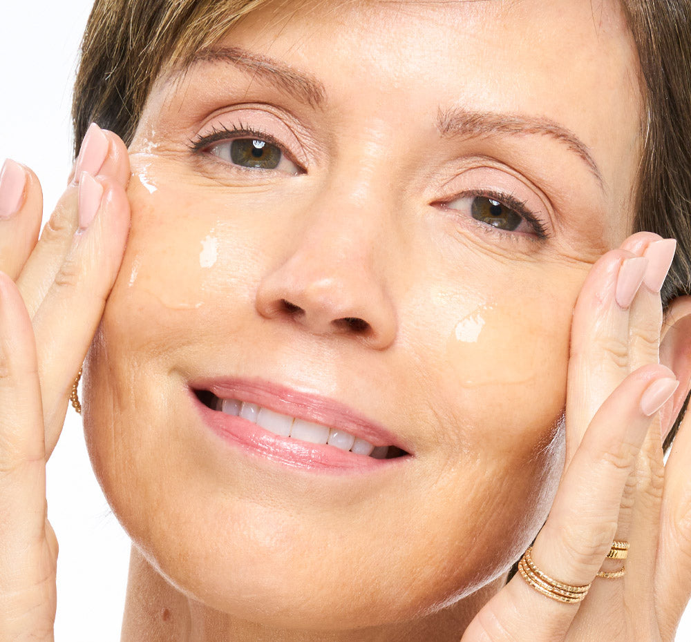Woman applying  FHF Exosome Booster X5 to her face with a white background