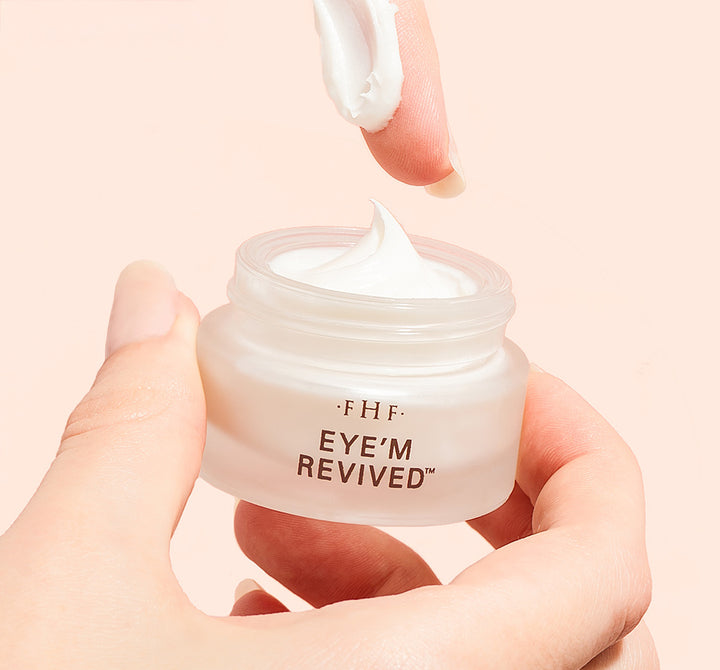 Hand holding a jar of 'EYE'M REVIVED' cream showing thick whipped texture 