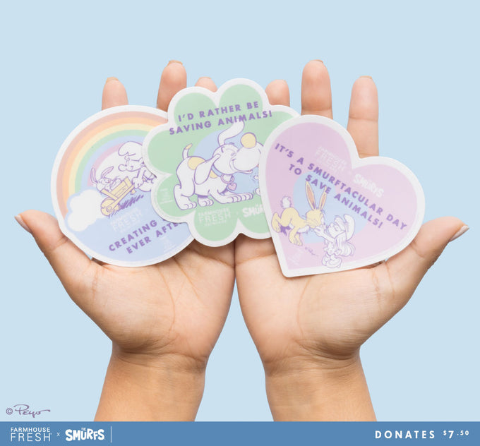 Hands holding three FarmHouse Fresh Smurf-sational Jumbo Stickers. All profits benefit animal rescue initiatives around the country.