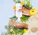 A woman is squeezing a small amount of FarmHouse Fresh Forest Flower Creamy Chamomile Cleanser onto her hand, showing the creamy texture of the product.
