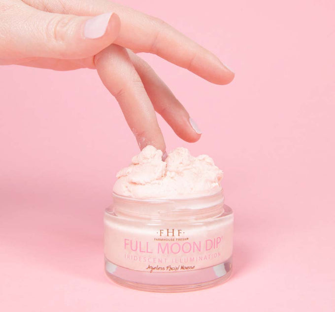 A woman dipping her finger in a jar of FarmHouse Fresh Full Moon Dip Illumination Mousse with Retinol + Wrinkle-Targeting Peptides.