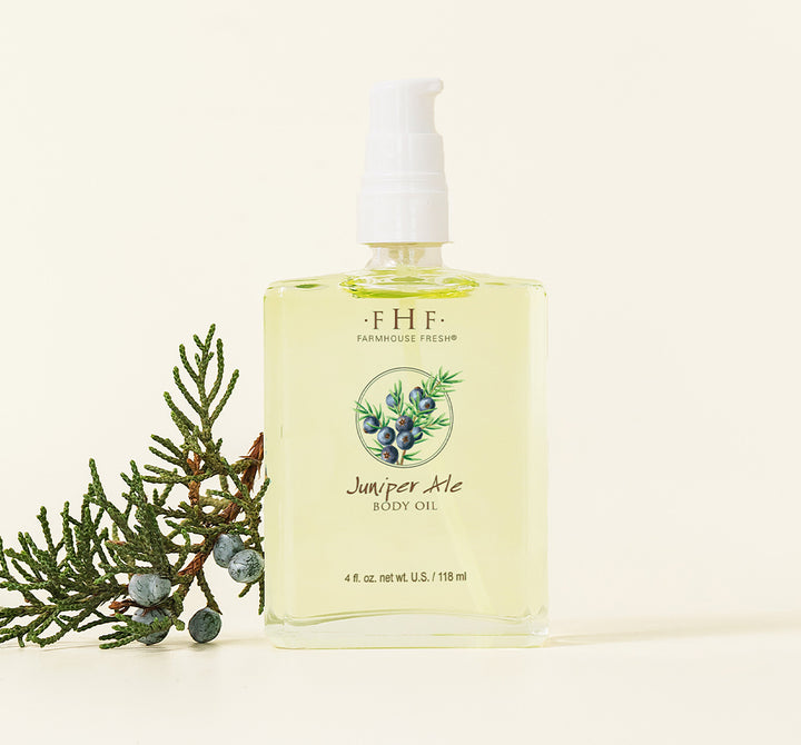 A bottle of Juniper Ale body oil by FarmHouse Fresh scented with fresh greens and bergamot orange.