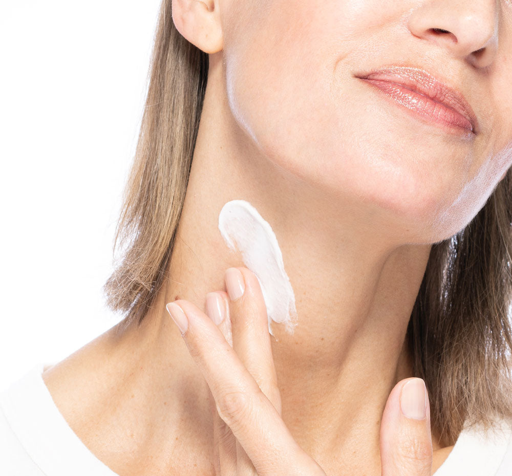 A woman is applying FarmHouse Fresh Necks-Level Smooth Neck Cream to make her neck smoother and younger looking.