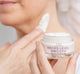 A woman is applying FarmHouse Fresh Necks-Level Smooth Neck Cream to smooth and hydrate her neck area.