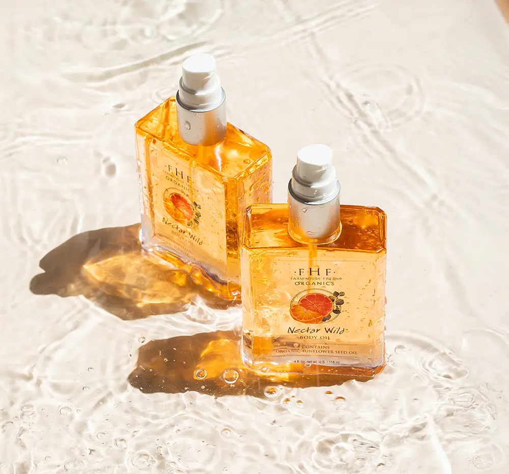 Two bottles of FHF Organics Nectar Wild body oil on a textured white surface.