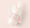 A Pink Moon shea butter body lotion and a texture smudge on a pink background.